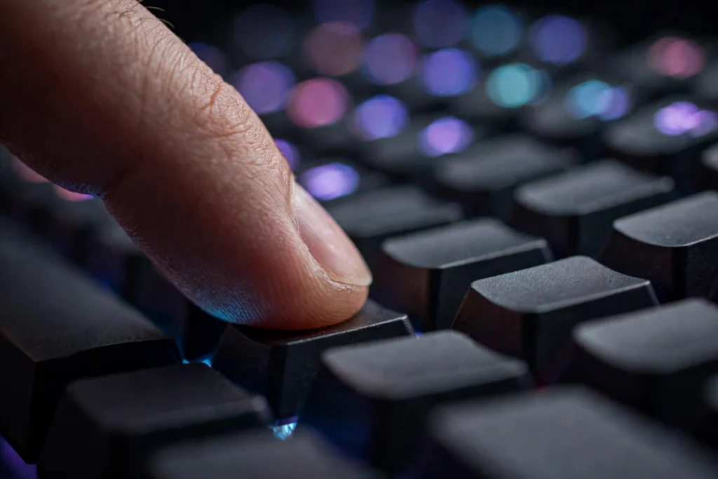 Close-up of a fingertip lightly pressing a key, showing the shallow actuation point used in starter rapid trigger settings.
